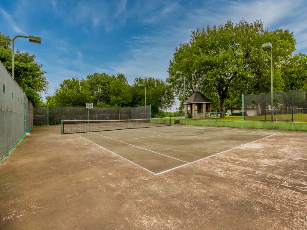 Full-size tennis court with perimeter fencing