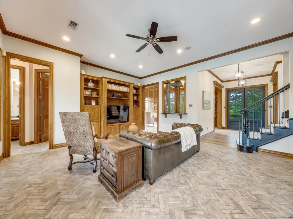 Living area featuring herringbone-pattern wood-finish flooring, a built-in entertainment center with shelving, recessed lighting, and a ceiling fan