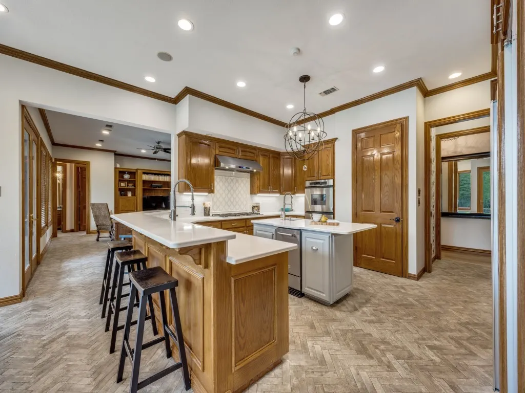 Gourmet kitchen featuring a central island with integrated seating, white countertops, built-in stainless steel appliances, and herringbone-patterned flooring