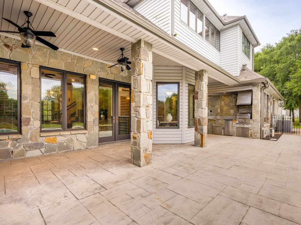 Expansive stamped concrete patio with stone veneer columns and exterior walls