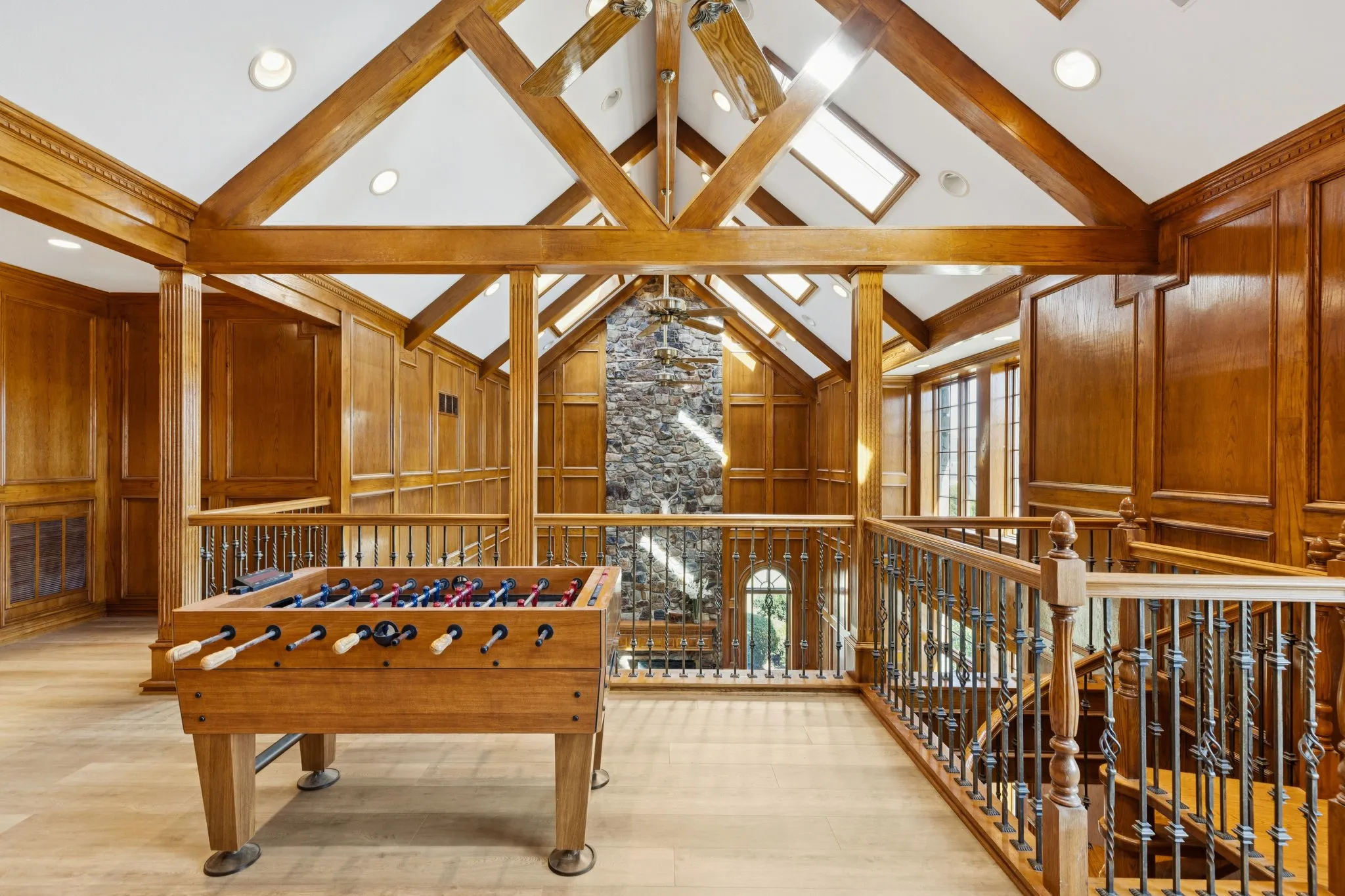 Loft space featuring wood-finish flooring, wood paneled walls, and a vaulted ceiling with exposed wood beams