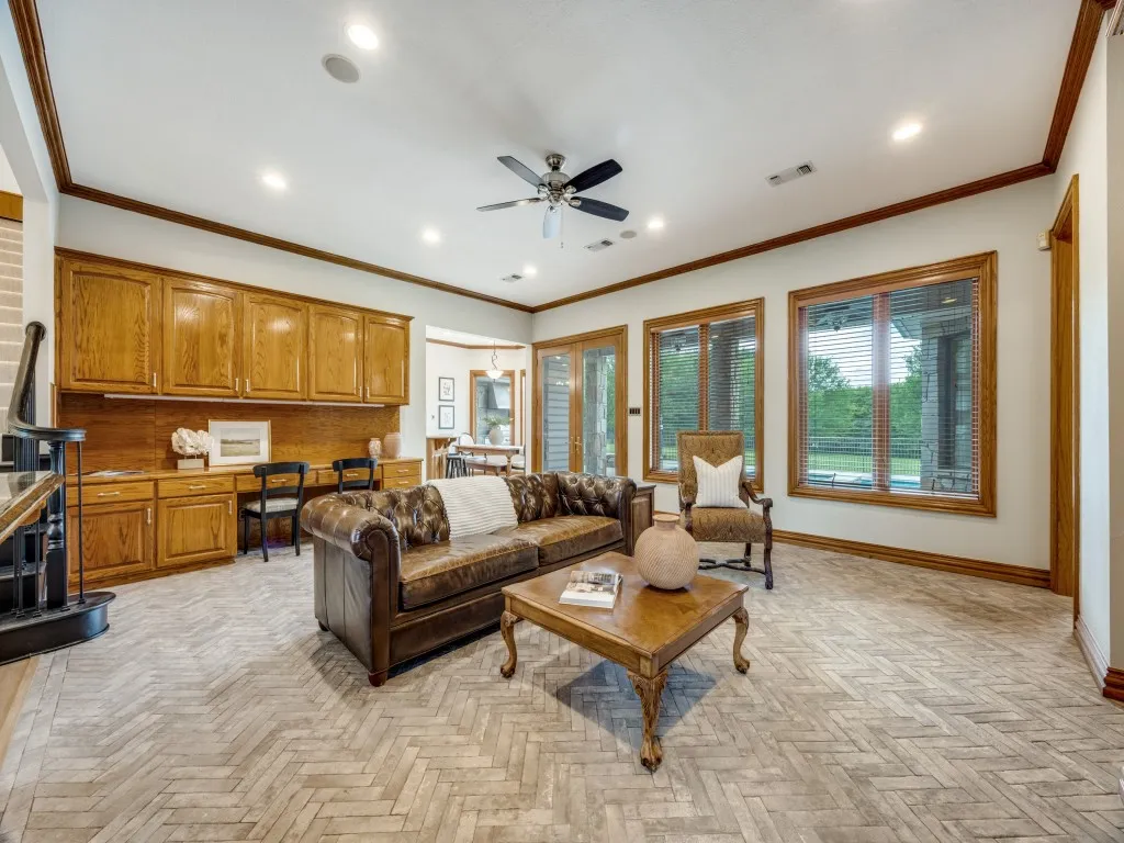 Herringbone pattern tile flooring extends throughout this expansive room, complemented by a built-in wood cabinetry desk unit