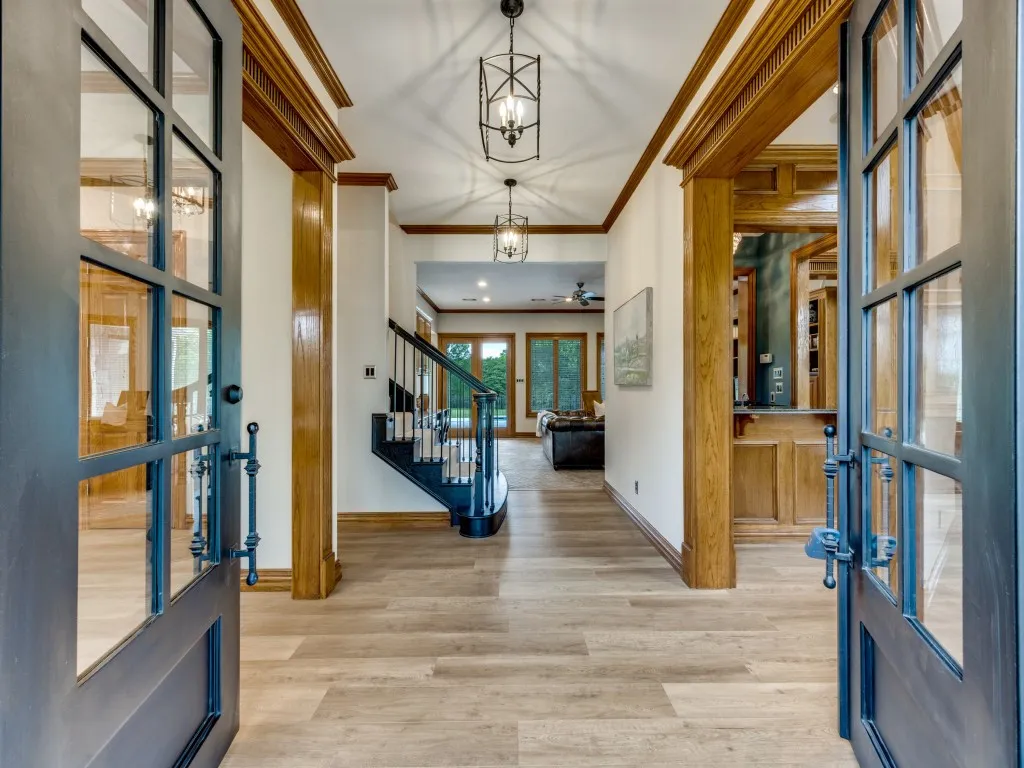 Entryway featuring wood-finish flooring, a dark-toned staircase with white risers and wrought iron balusters, and overhead lantern-style pendant lighting
