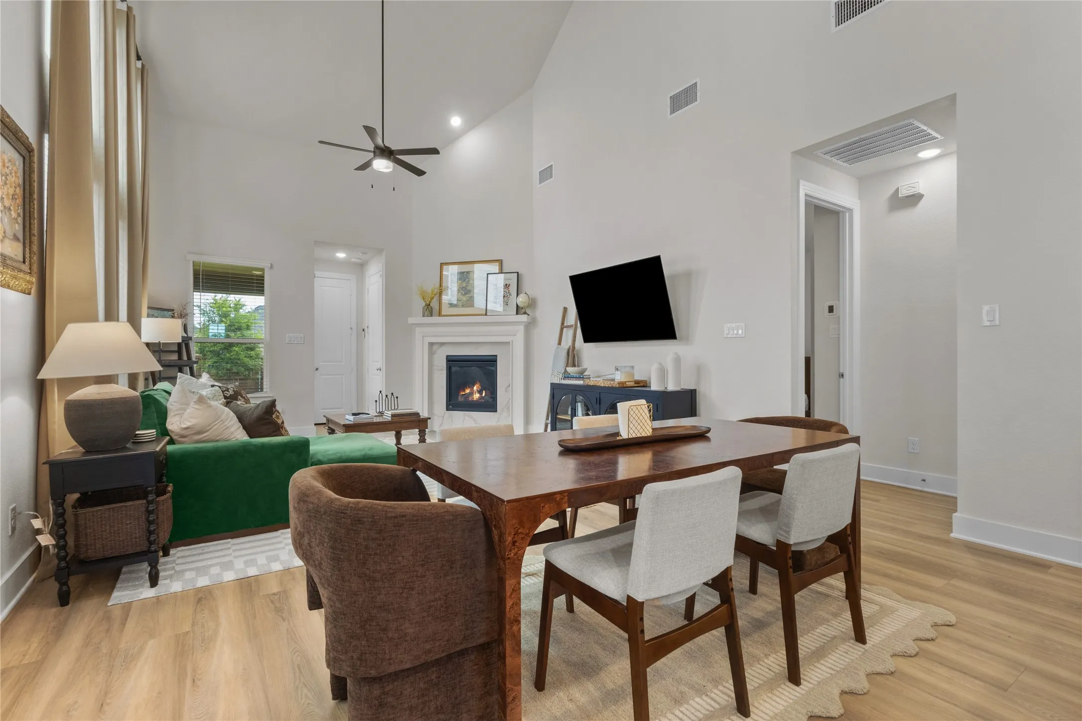 Vaulted ceilings above a dining area and living room featuring a fireplace with a white mantel, recessed lighting, and wood-finish flooring