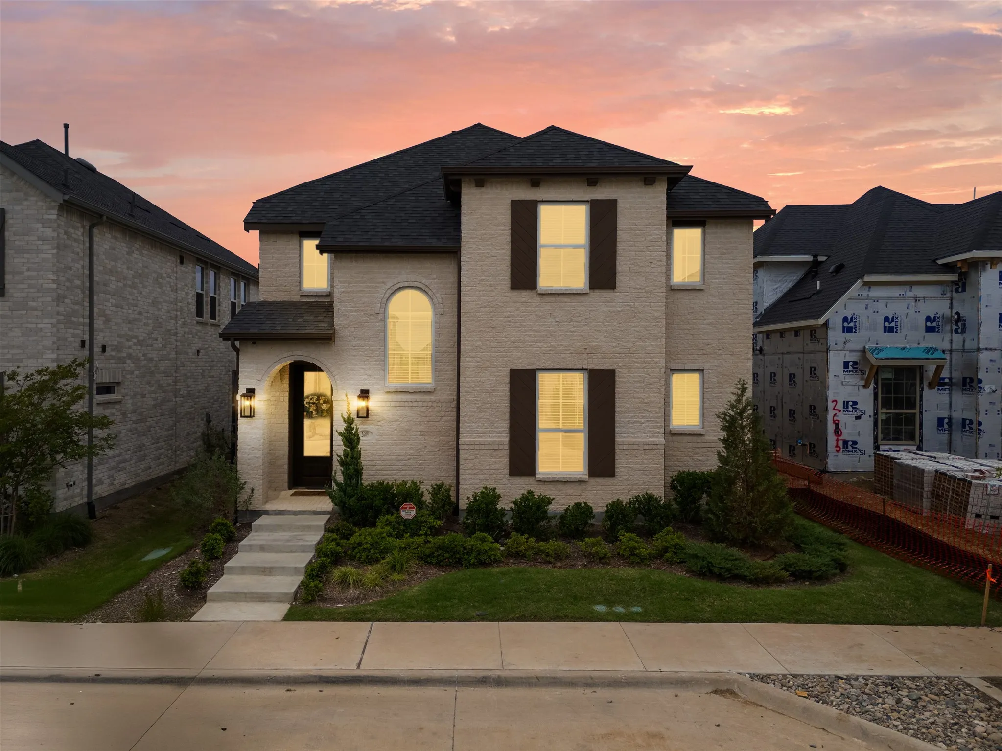 Two-story residence featuring light-colored brick facade and dark roof