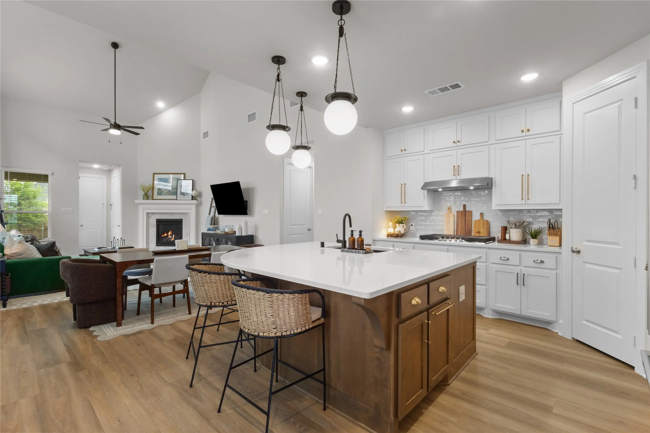 Open-concept space featuring a kitchen island with seating, white cabinetry, and stainless steel appliances