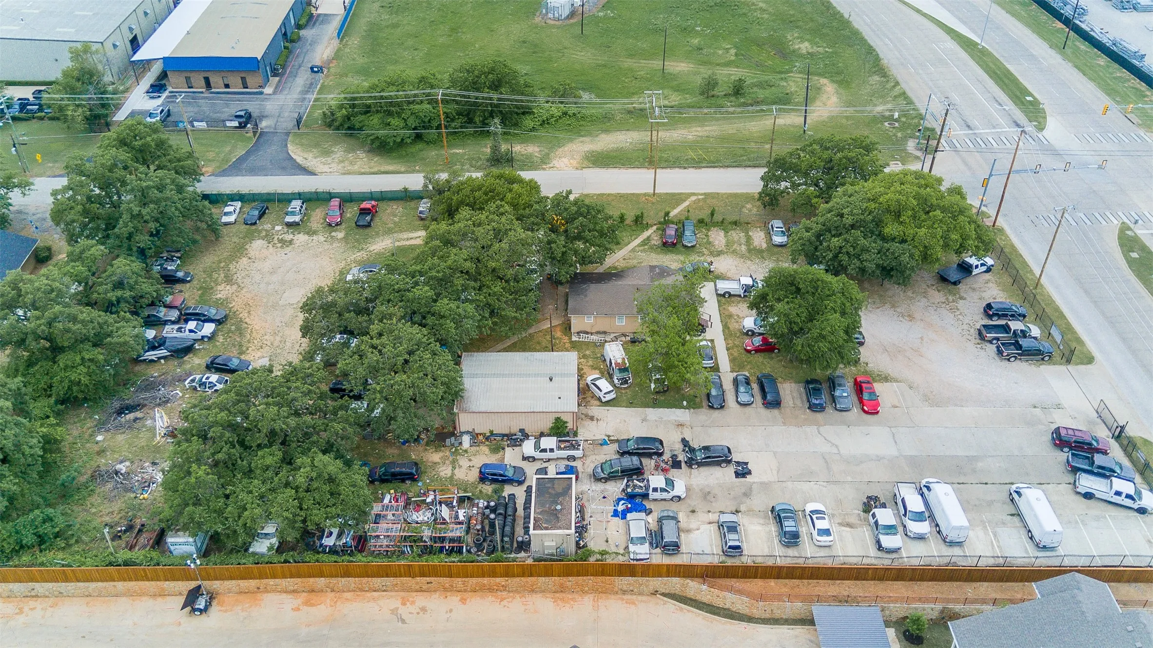 Expansive commercial property featuring multiple structures, paved parking areas, mature trees, and direct access to major roadways