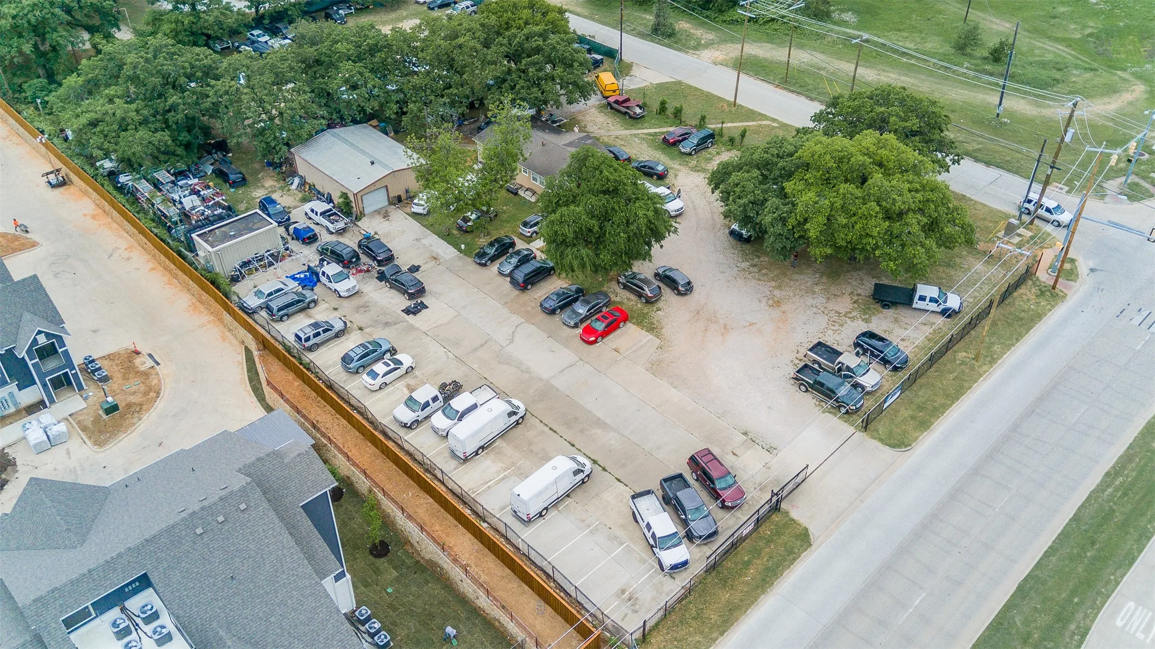 Expansive commercial property featuring a large asphalt parking lot, concrete driveways, and a metal-roofed industrial building