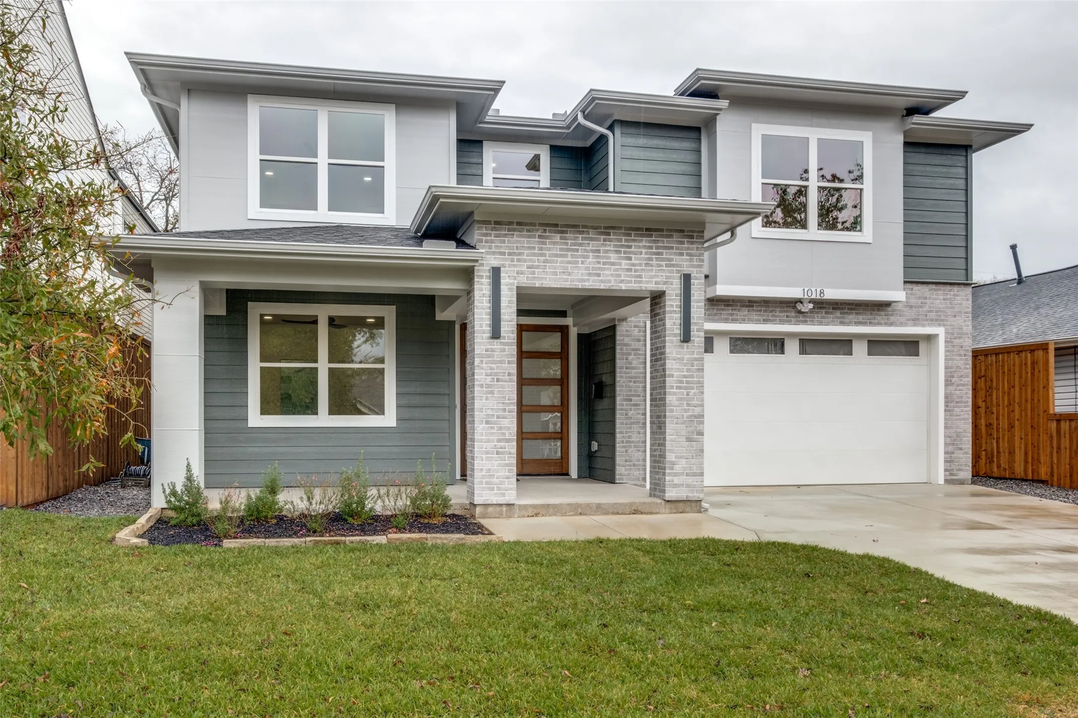 View of front of home featuring brick siding, driveway, and a garage
