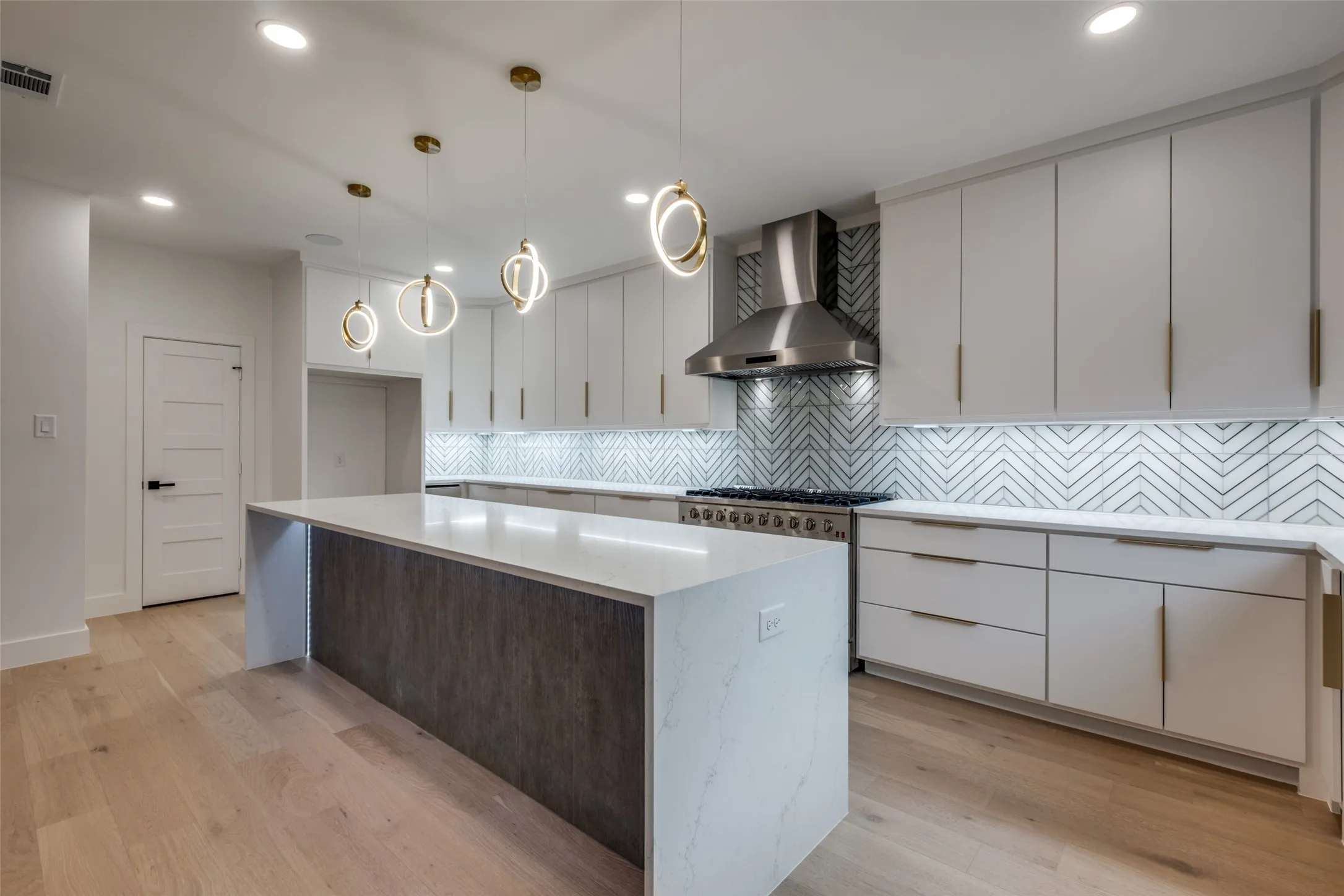 Kitchen featuring white cabinets, wall chimney exhaust hood, hanging light fixtures, modern cabinets, and tiled backsplash