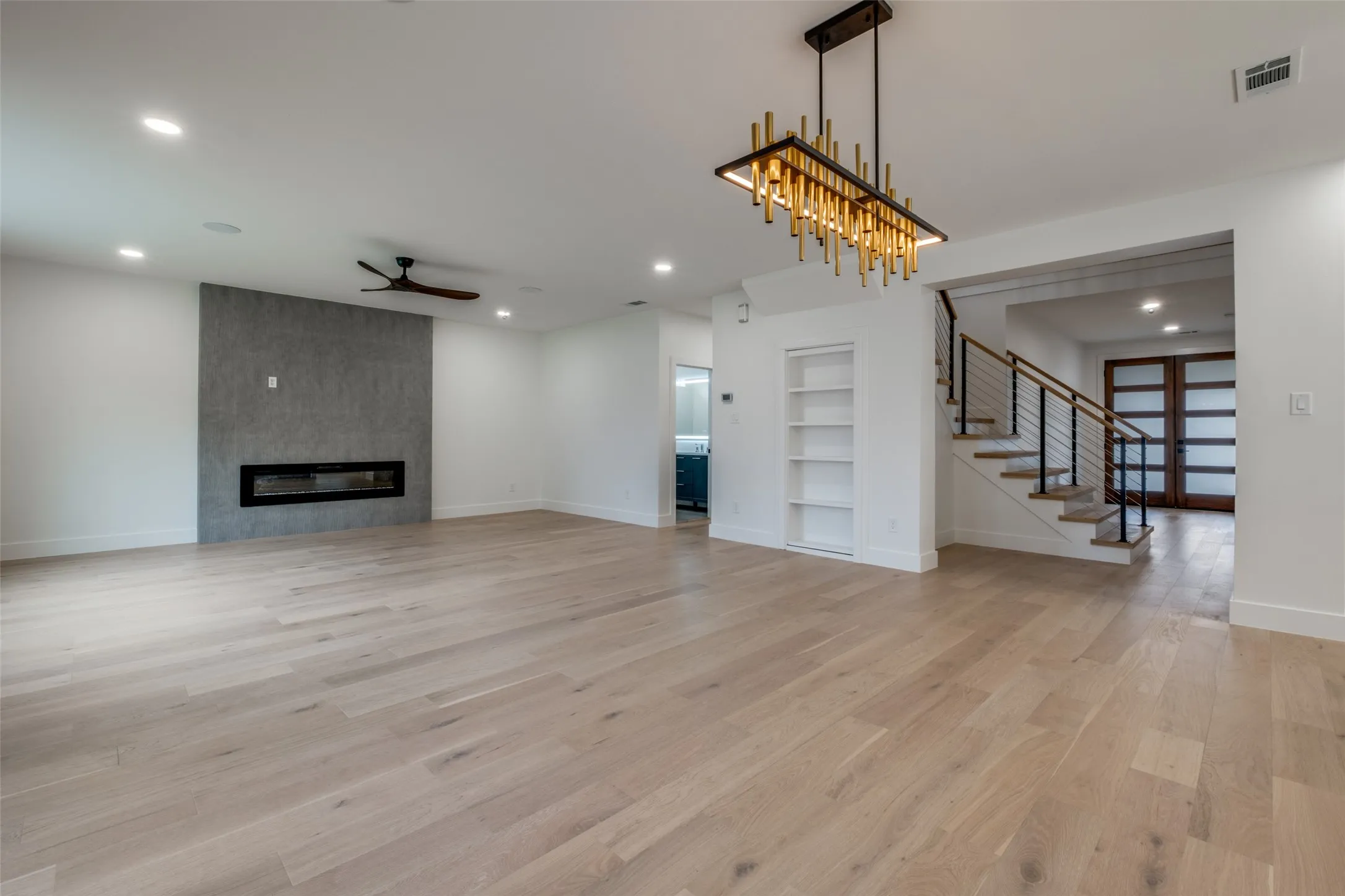 Living room featuring built in features, light wood-type flooring, stairway, recessed lighting, and a ceiling fan - Open dining area