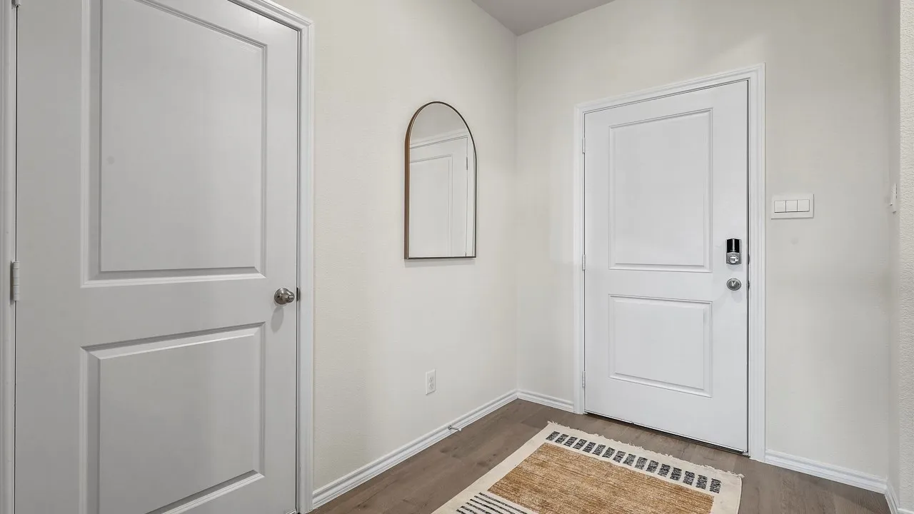 Entryway featuring wood-finish flooring, white walls, and a paneled door with a smart lock system