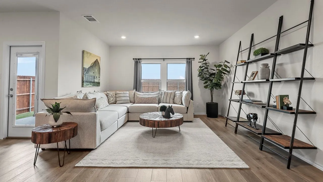 Spacious living area featuring light wood-finish flooring, recessed lighting, and ample natural light from multiple windows