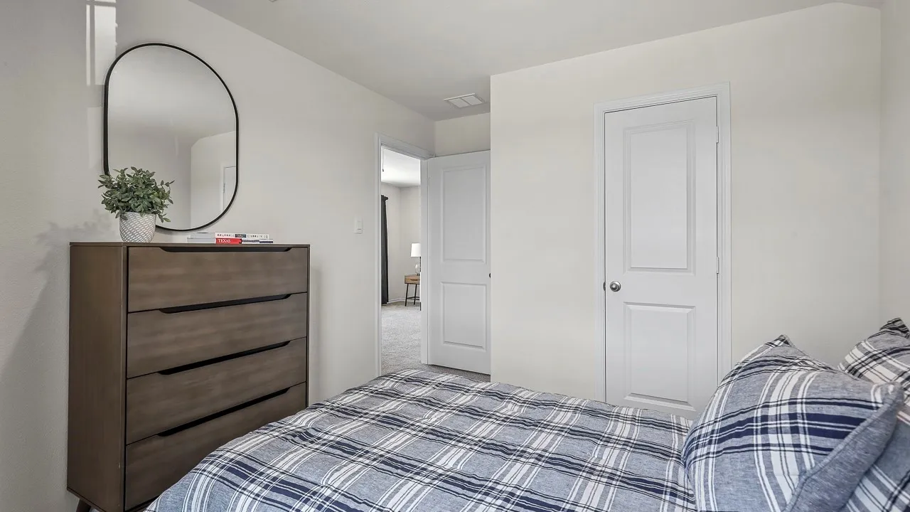 Bedroom featuring light-toned walls, a white paneled door, and neutral-colored carpeting