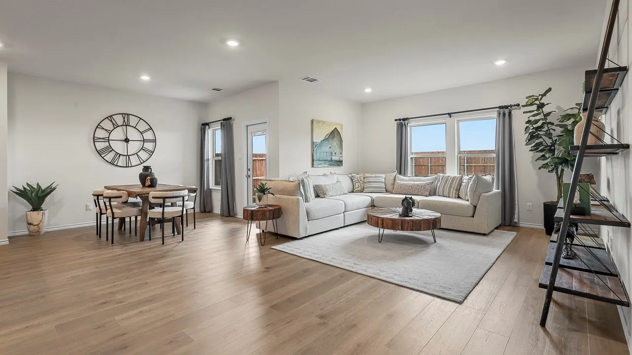 Open-concept living area featuring wood-finish flooring, recessed lighting, multiple windows, and a dining area with direct outdoor access