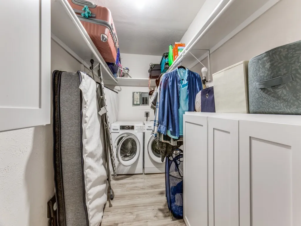 Washroom featuring washer and dryer, light wood finished floors, and electric panel