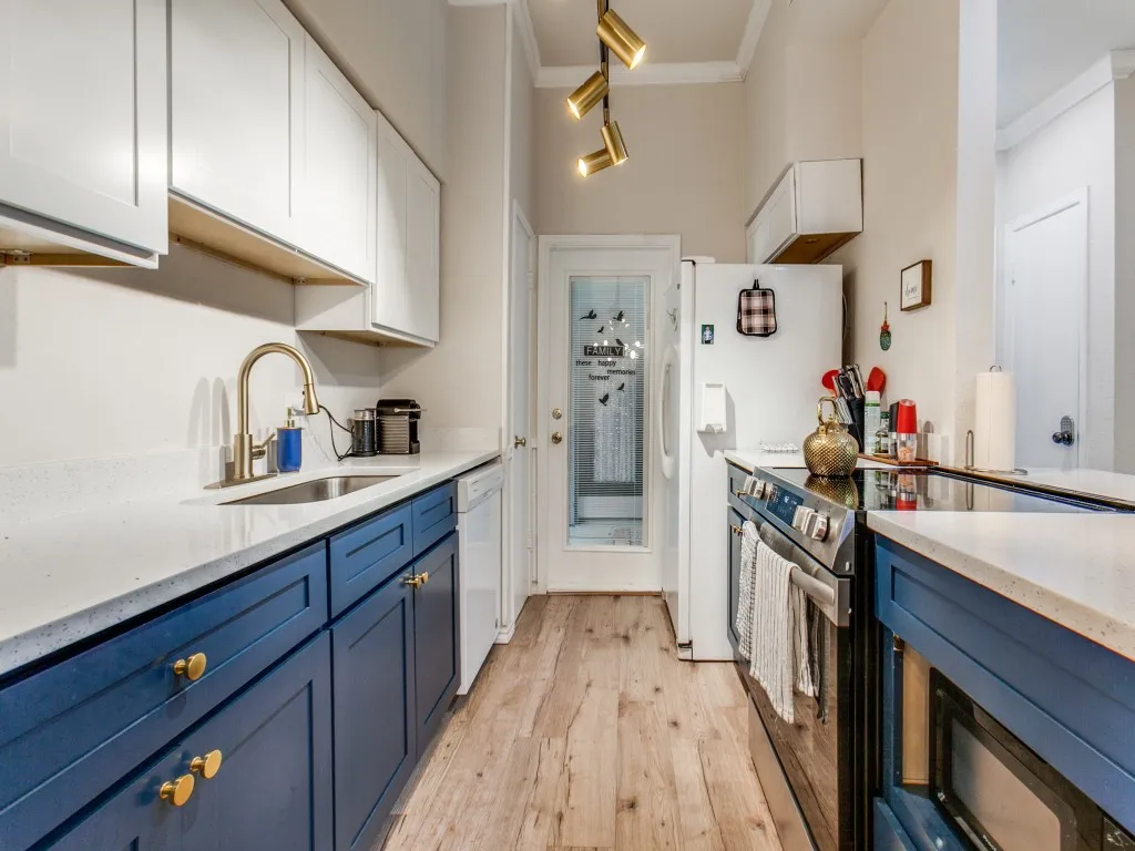 Kitchen featuring blue cabinets, white appliances, light wood-style floors, light stone countertops, and white cabinetry