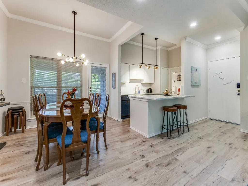 Dining area with a chandelier, light wood-style floors, and ornamental molding