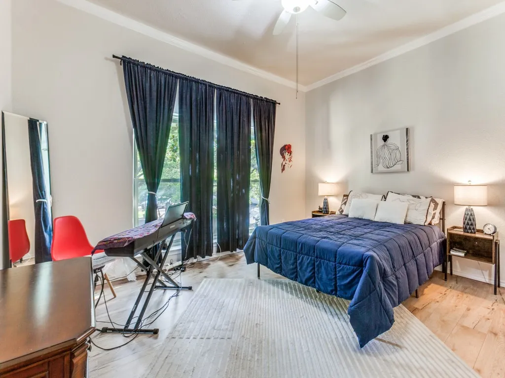 Bedroom with ornamental molding, light wood-type flooring, and ceiling fan