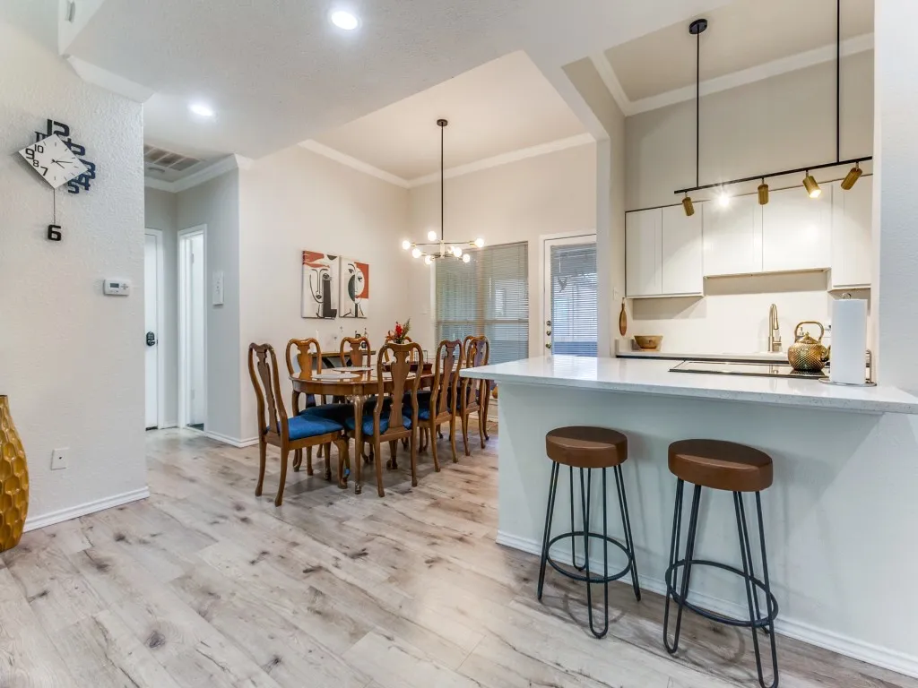 Kitchen featuring white cabinetry, ornamental molding, light wood-style floors, a kitchen breakfast bar, and a peninsula