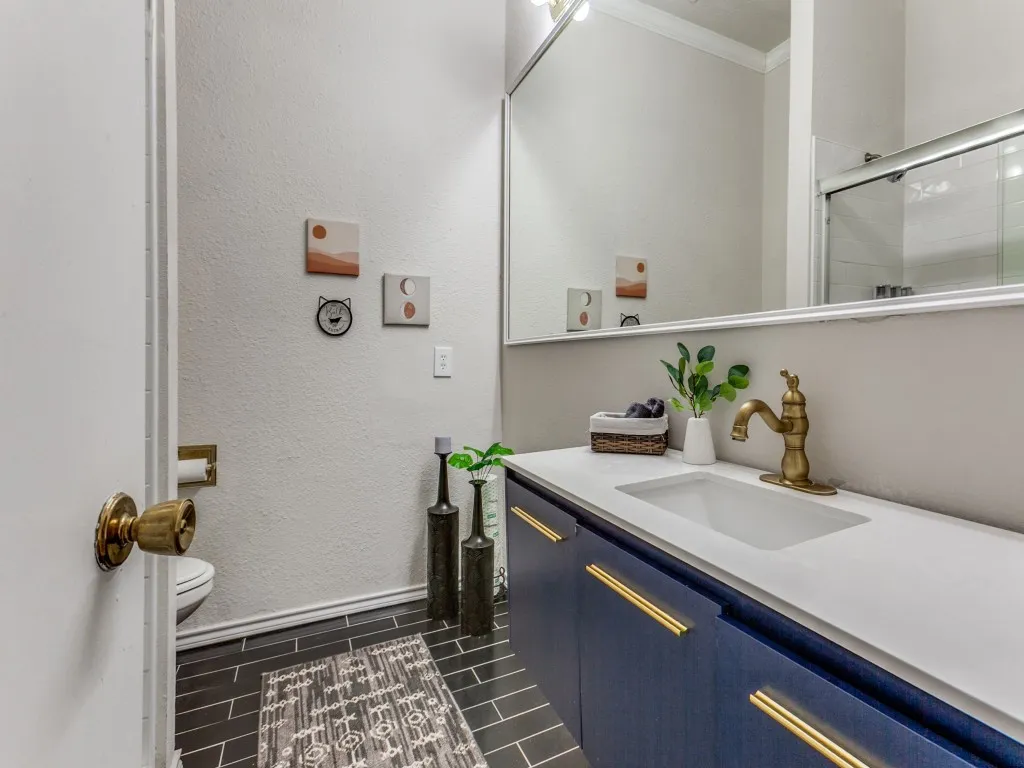 Bathroom with vanity, a textured wall, and tiled shower