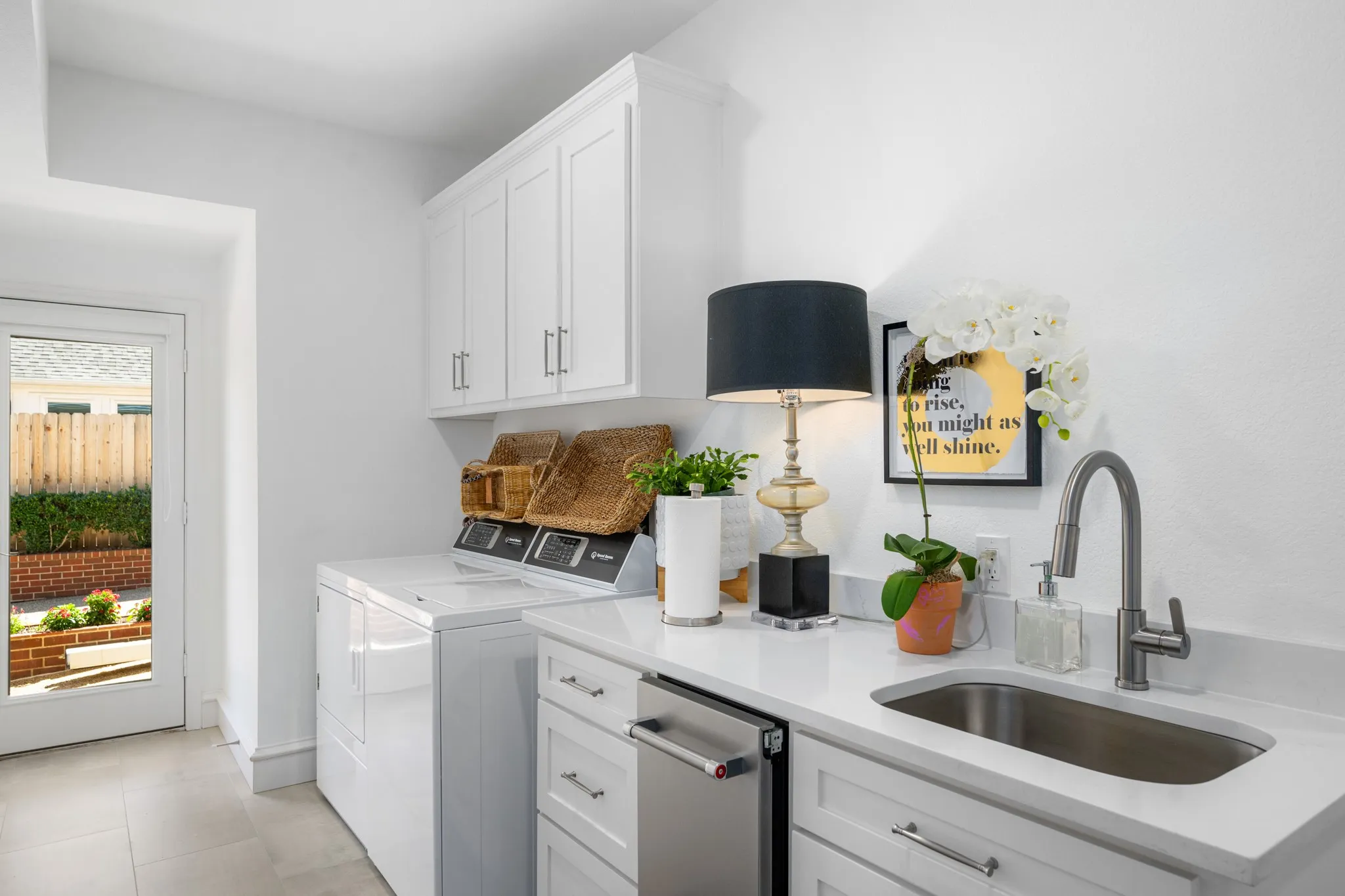 Laundry room features a sink, extra storage closet, built-in ice maker and exterior door to driveway.