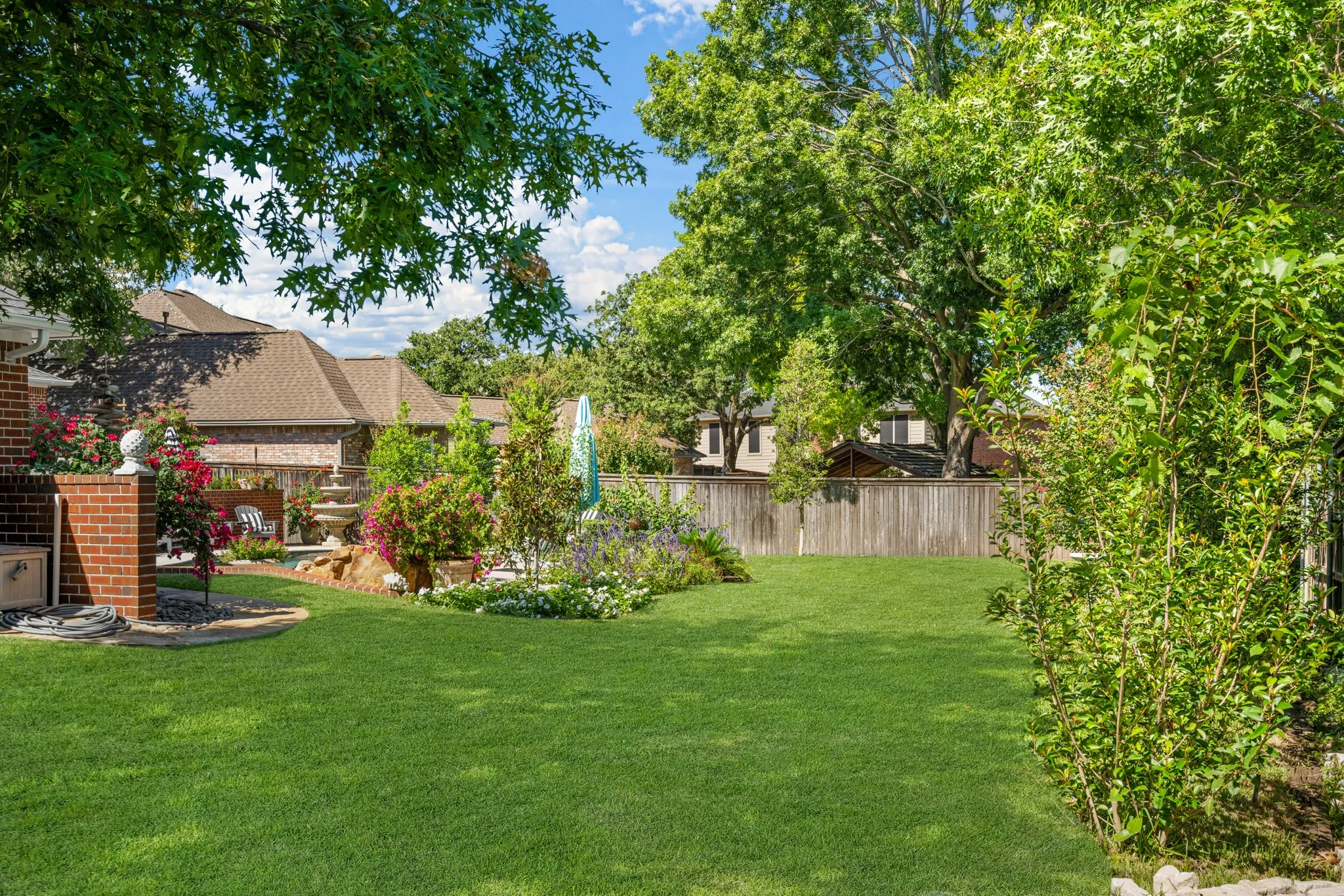 The green yard and lush landscaping is beautifully maintained by use of the sprinkler system.
