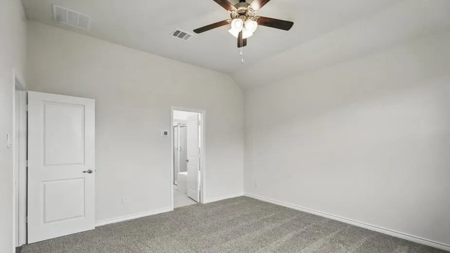 Spacious interior room featuring vaulted ceilings, a ceiling fan with integrated lighting, and neutral grey carpet flooring