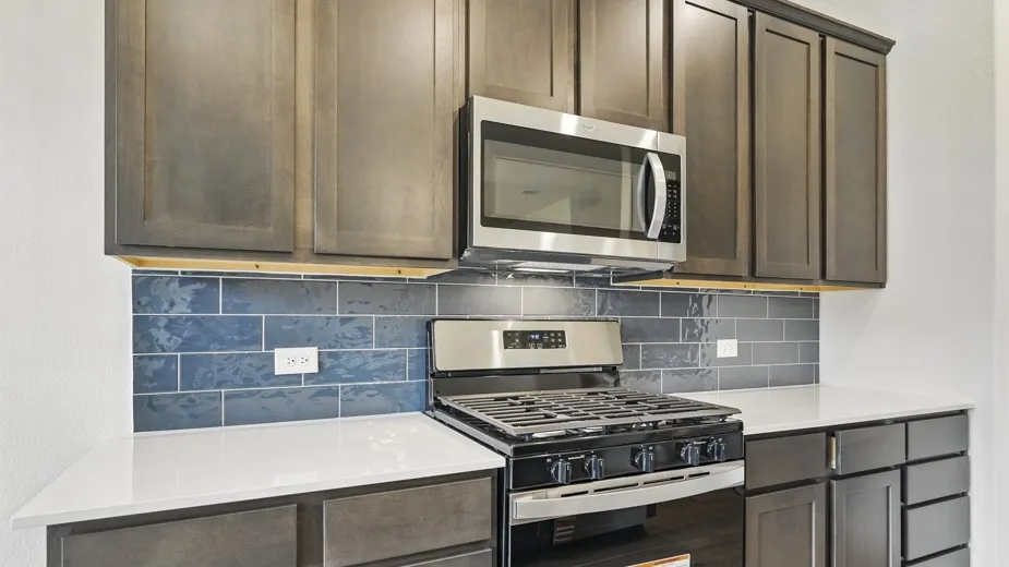 Kitchen featuring dark wood-finish cabinetry, white countertops, and a blue subway tile backsplash