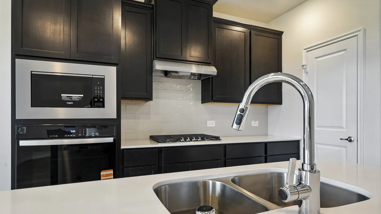 Kitchen featuring dark wood cabinetry, white subway tile backsplash, stainless steel appliances, and light-toned countertops