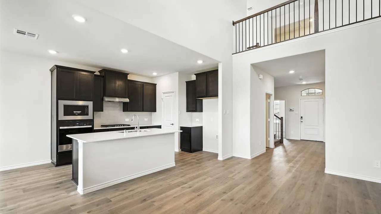 Open-concept living space featuring a kitchen island with sink, dark wood cabinetry, and stainless steel appliances