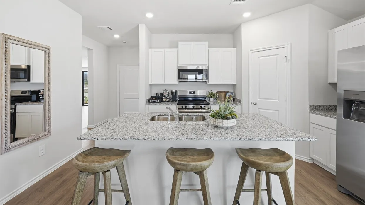 Open-concept kitchen featuring an oversized island with ample counter space and a stainless steel double basin sink