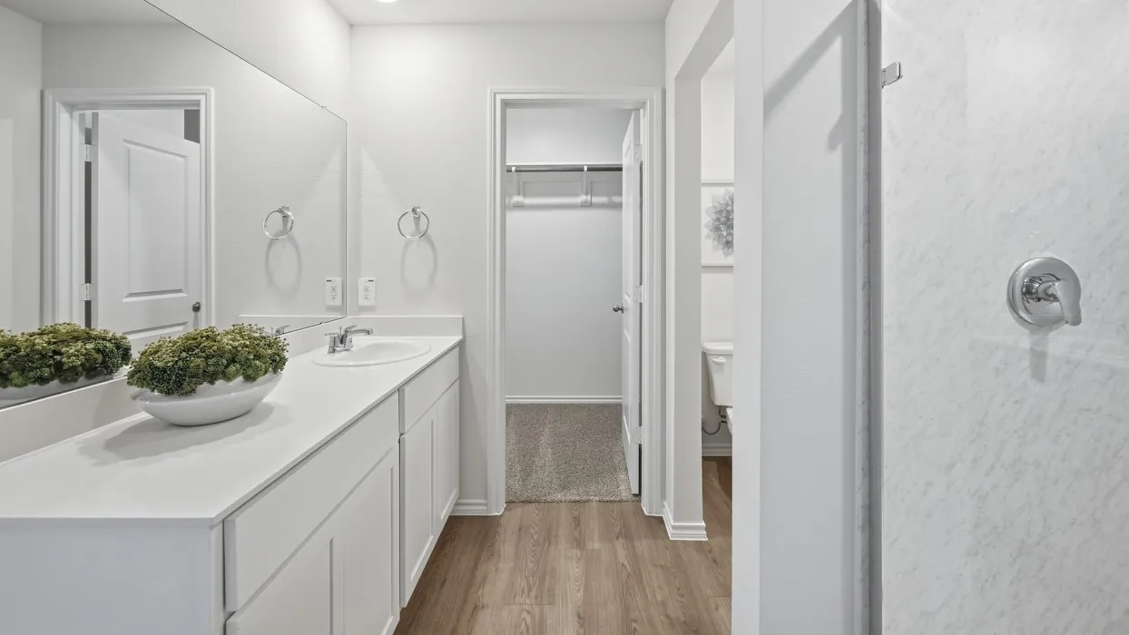 Bathroom featuring a long vanity with dual sinks and white cabinetry