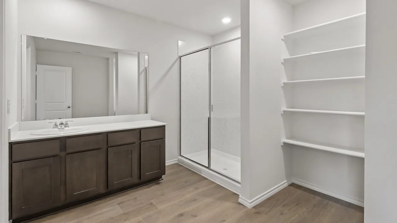 Bathroom featuring a dark wood-finish vanity with a single basin sink and a large mirror
