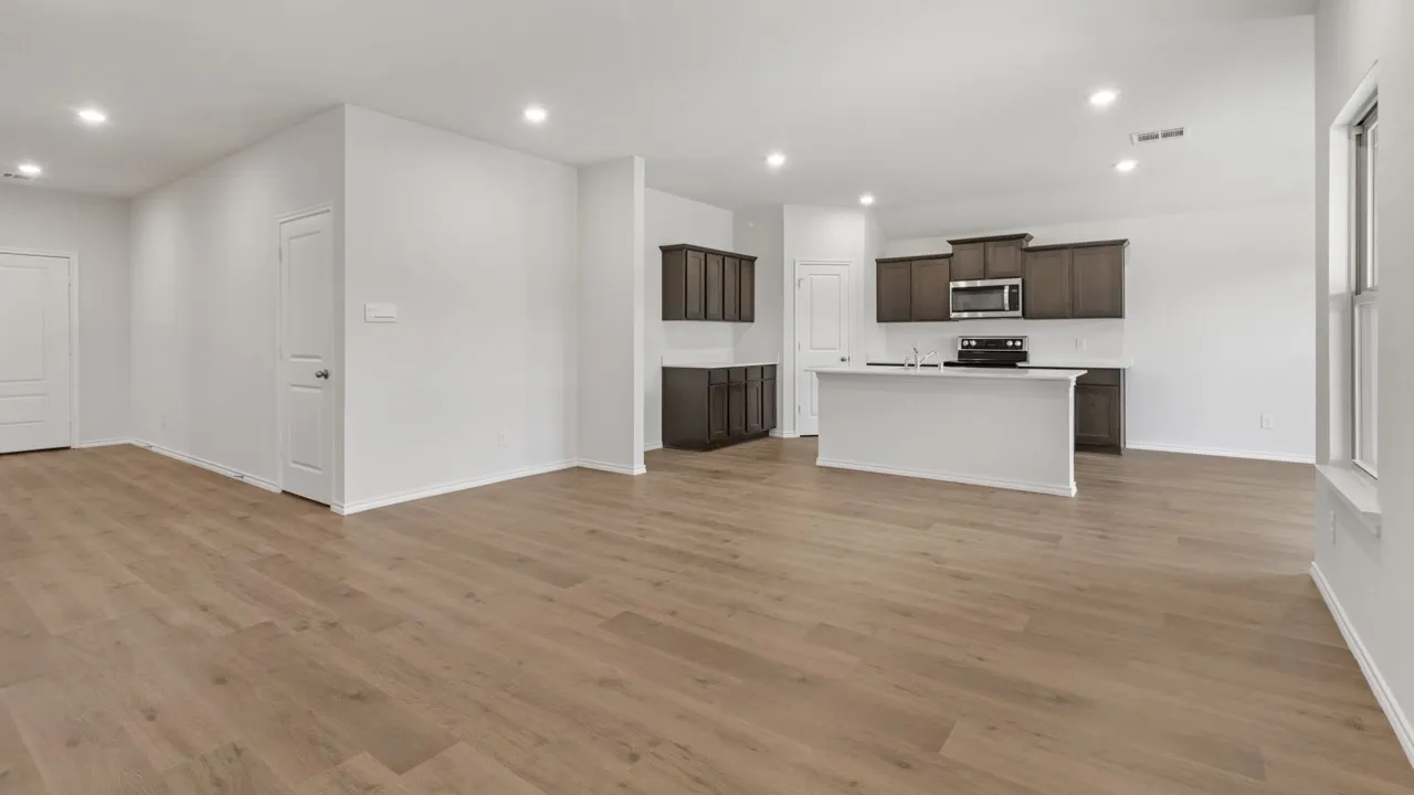 Spacious open-concept living area featuring wood-finish flooring, recessed lighting, and a kitchen island with seating