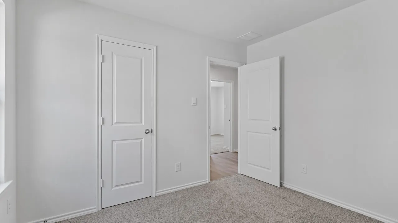 Neutral tone wall paint with crisp white trim, featuring plush grey carpeting and two panel doors
