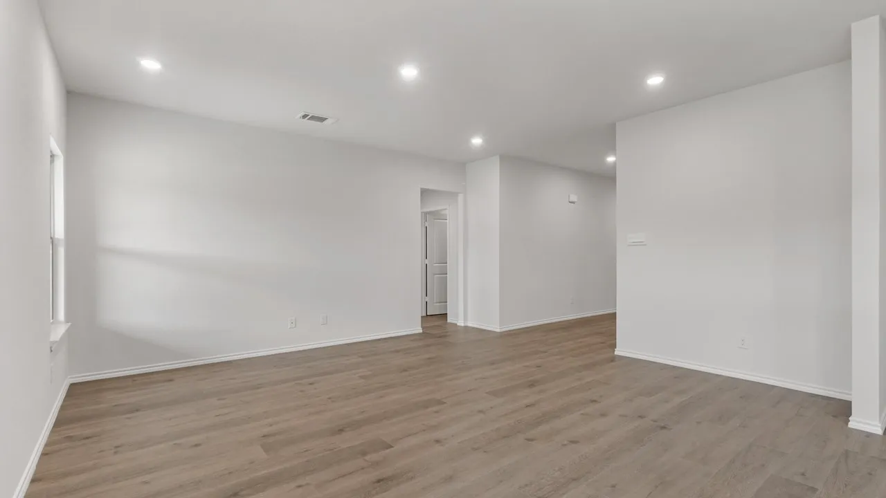 Spacious interior room featuring wood-finish flooring, recessed lighting, and crisp white walls