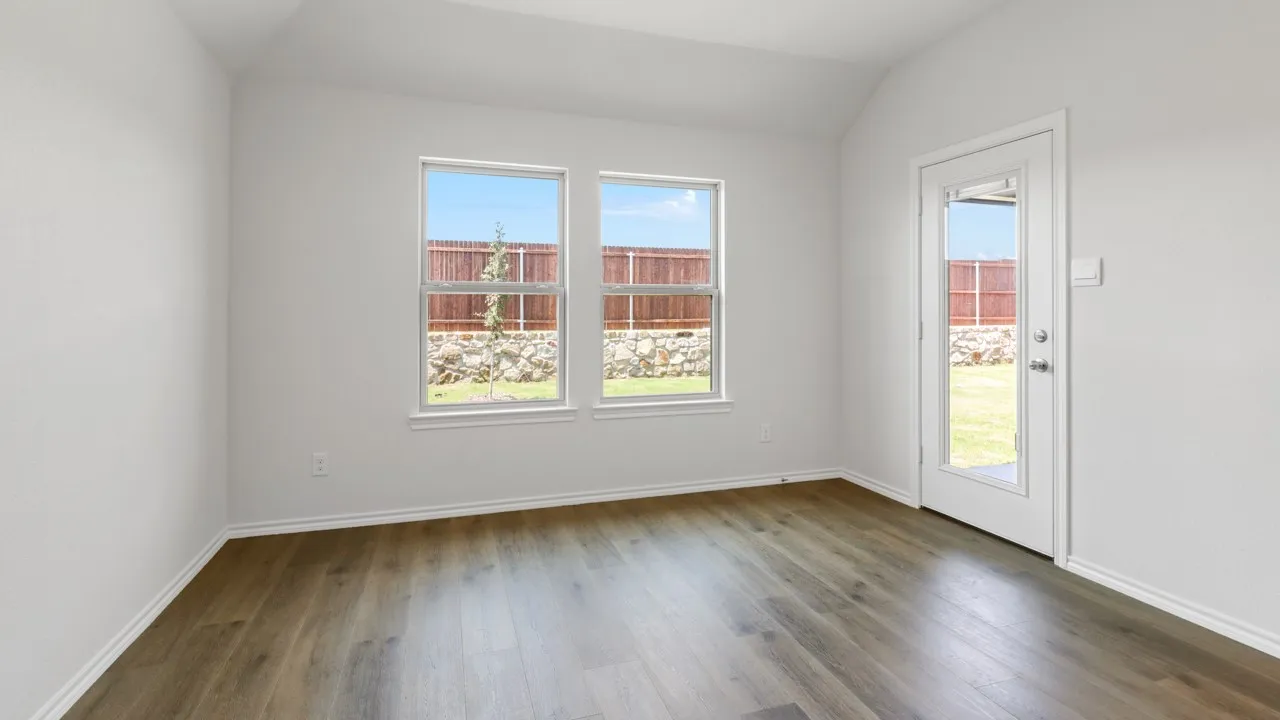 Room with wood-finish flooring, vaulted ceiling, and white baseboards