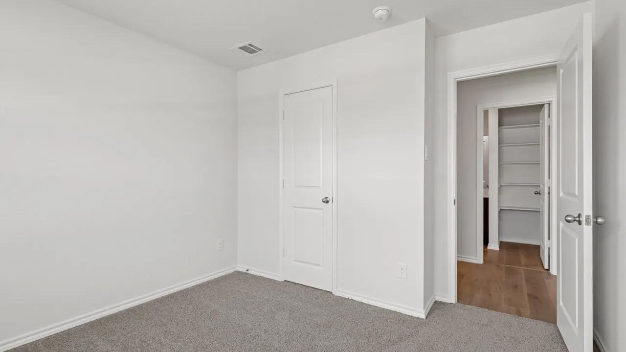 Neutral tone paint throughout, featuring a textured carpet flooring, white trim, and white doors