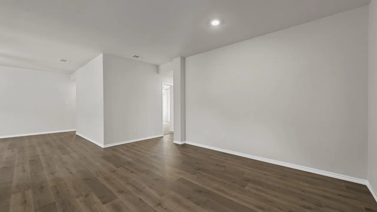 Spacious room featuring wood-finish flooring, light gray wall paint, white trim, and recessed ceiling lighting