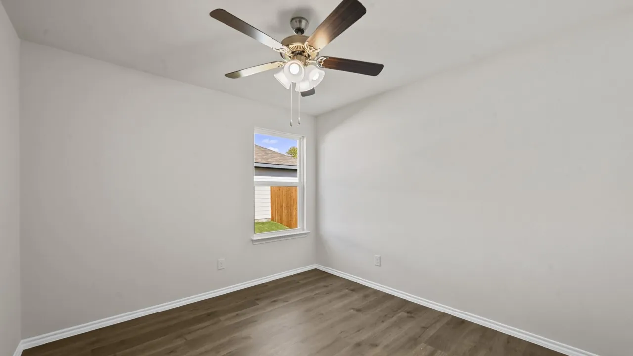 Interior room featuring wood-finish flooring, light-toned walls, and a ceiling fan with integrated lighting