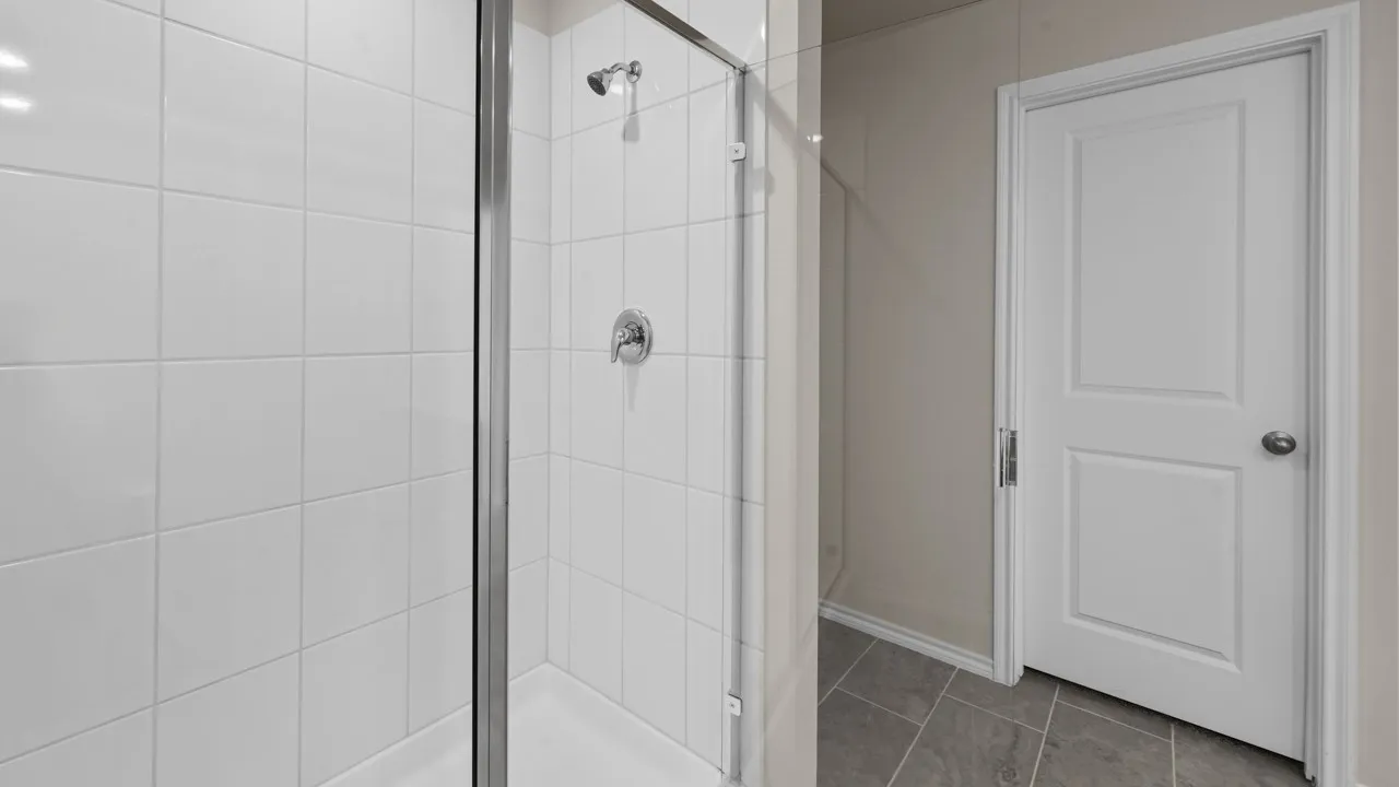 Walk-in shower with clear glass enclosure and chrome fixtures