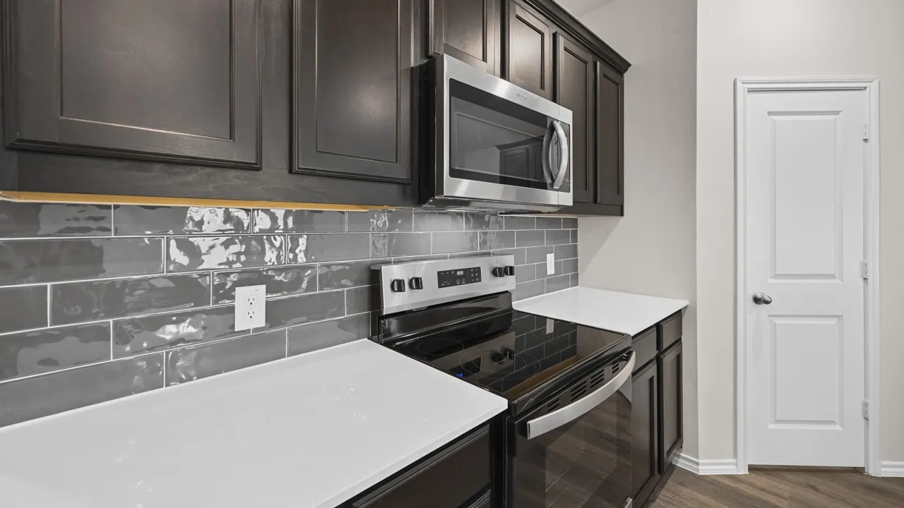 Contemporary kitchen featuring dark wood cabinetry, stainless steel microwave, and electric range