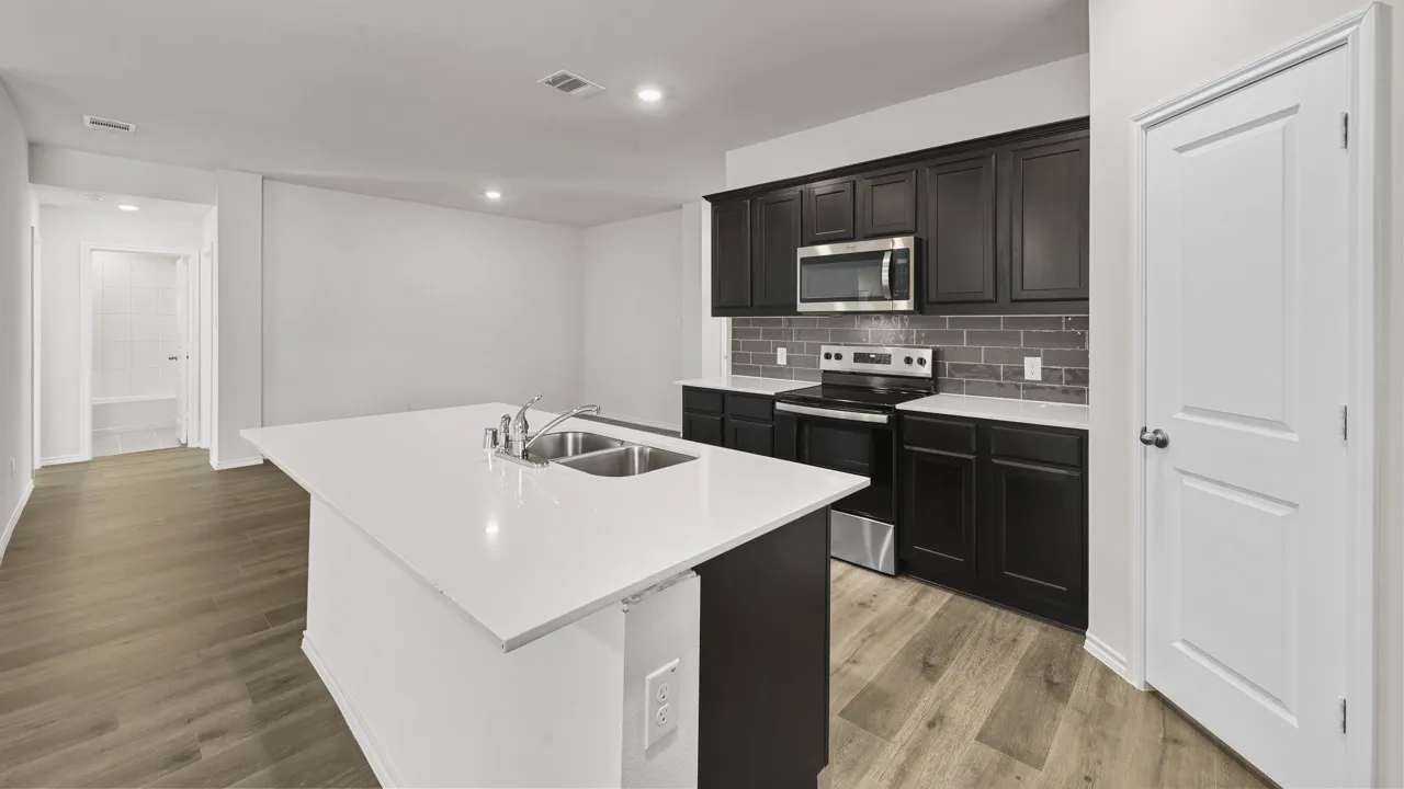 Kitchen with white countertop island featuring a double-basin stainless steel sink, dark wood-finish cabinetry, stainless steel appliances, and a gray subway tile backsplash