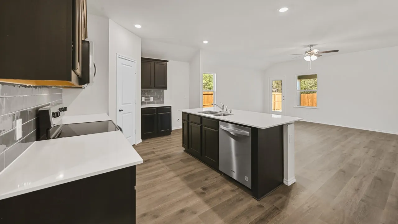 Open-concept kitchen and living area featuring a central island with sink, stainless steel dishwasher, and white countertops