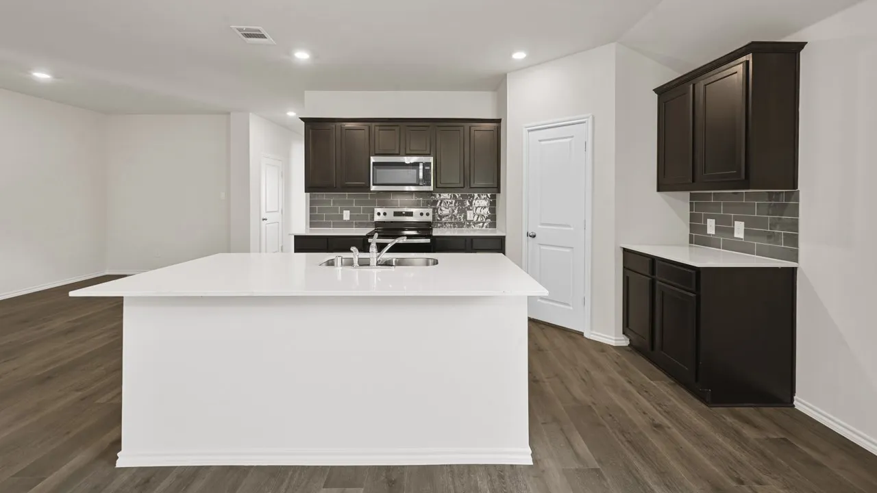 Kitchen featuring a large white island with integrated sink, dark wood cabinetry, stainless steel appliances, and a gray subway tile backsplash