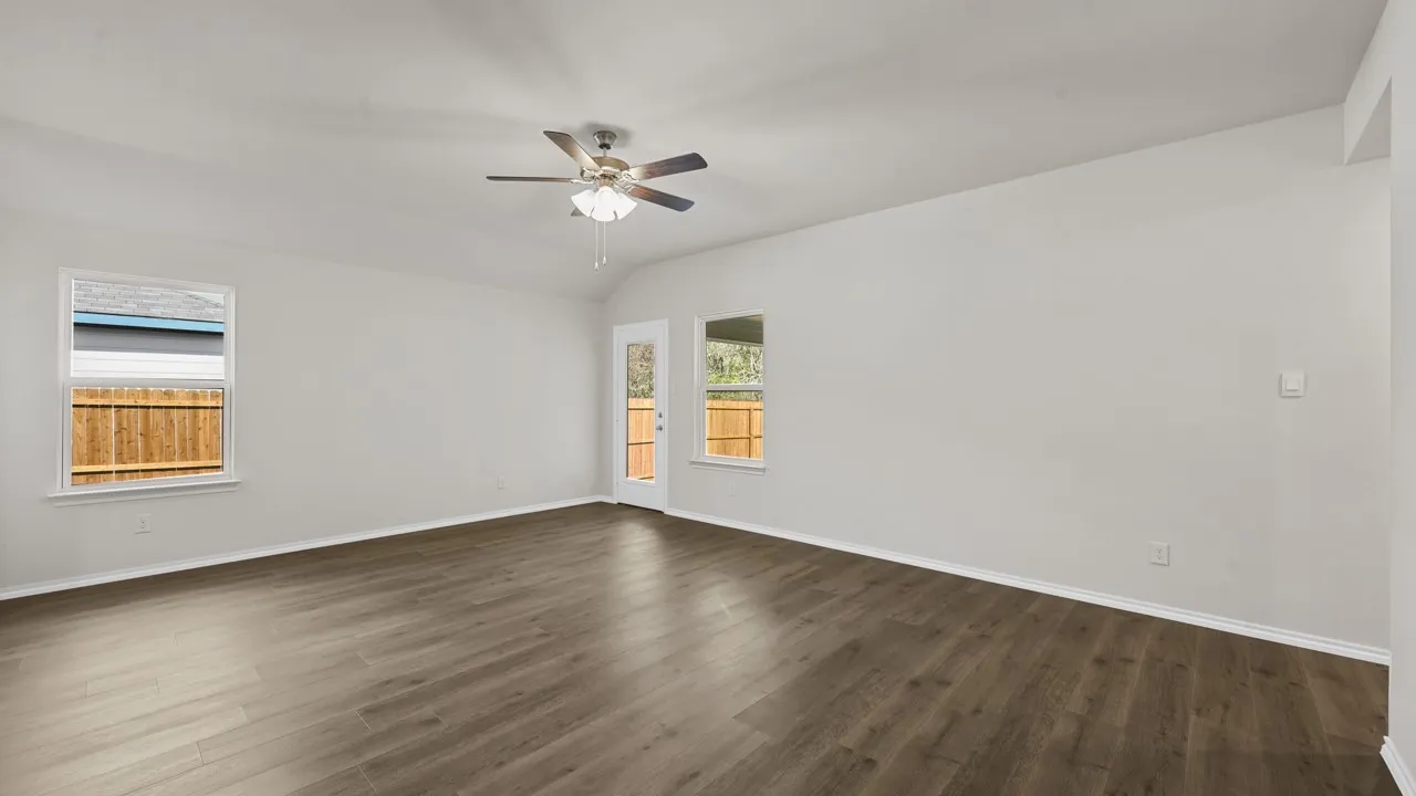 Spacious interior room featuring wood-finish flooring, white baseboards, and neutral wall paint