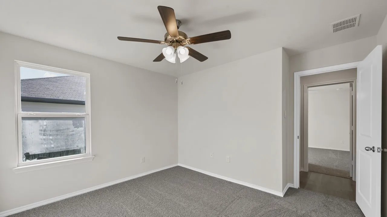 Room featuring neutral wall paint, gray carpeting, a window with white trim, a ceiling fan with light fixture, and white baseboards