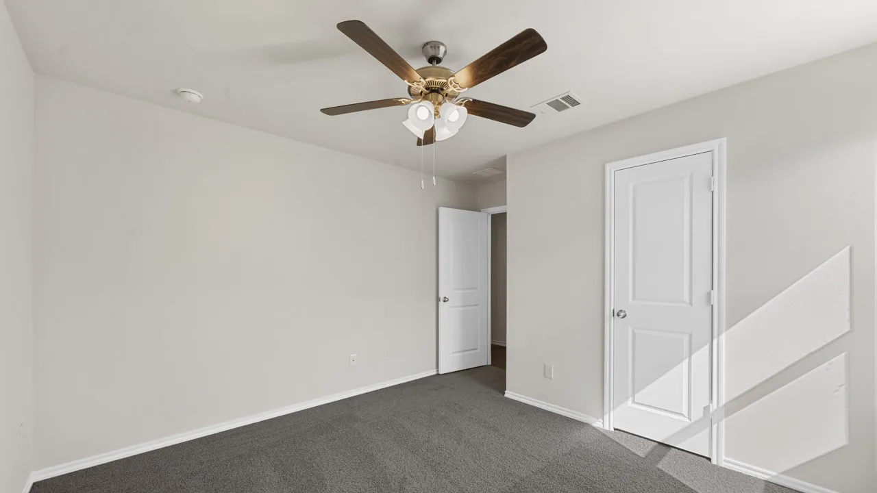Neutral-toned room featuring a ceiling fan with light fixture, carpet flooring, and white trim