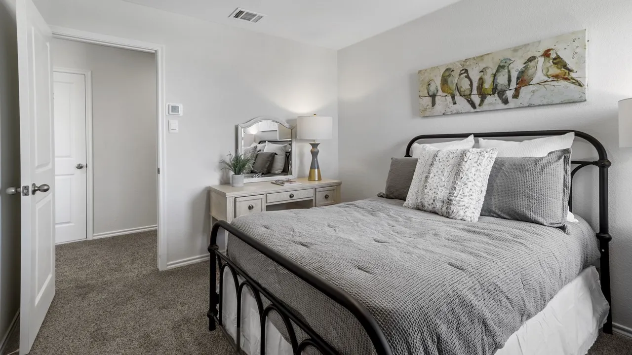 Carpeted bedroom featuring light gray walls, a white two-panel door, and a thermostat